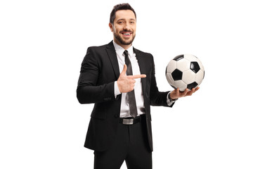 Canvas Print - Professional man in a black suit holding a soccer ball and pointing