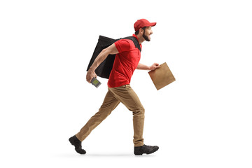 Wall Mural - Full length profile shot of a man running with a bag and a payment terminal and delivering food