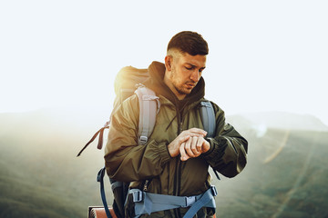 Young male traveler looking at his smart watch