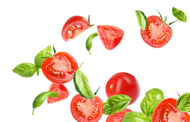 Many tomatoes and basil leaves falling on white background