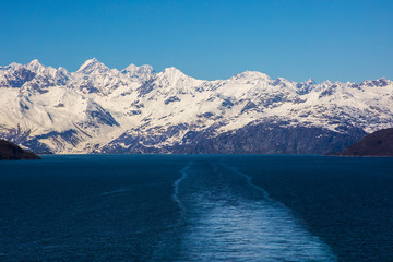 Glacier Bay Alaska cruise vacation travel. Global warming and climate change concept with melting ice. Cruising boat towards landscape of Johns Hopkins Glacier and Mount Fairweather Range mountains.