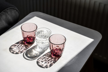 Crystal red glass on white table. Hard shadows in sunlight.