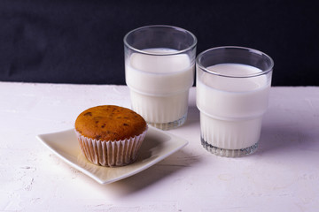 Cupcakes with two glasses of milk on a white and black background