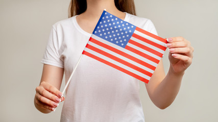 USA flag. United states of America. Patriotic woman in white holding official national symbol with red white stripes 50 stars on blue isolated on blur light background. Independence democracy.