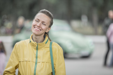 Wall Mural -  Excited young woman and her new car behind her. Young and cheerful woman enjoying new car and warm autumn or spring days