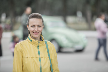 Wall Mural -  Excited young woman and her new car behind her. Young and cheerful woman enjoying new car and warm autumn or spring days