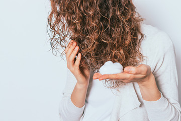 Woman's hands styling mousse used to her curly hair