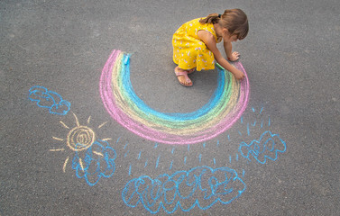 Wall Mural - A child draws a rainbow on the asphalt. Selective focus.