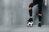 Fototapeta Sport - Woman legs with shoes and a soccer ball. Workout online concept. Vintage color filter