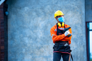 Fototapete - Electrician wearing protective mask to Protect Against Covid-19 standing in front of new house with electrician kits.