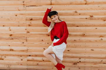 Wall Mural - Lovely blonde girl being crazy and funny on the wooden background. Beautiful woman in trendy white dress having great time outdoor.