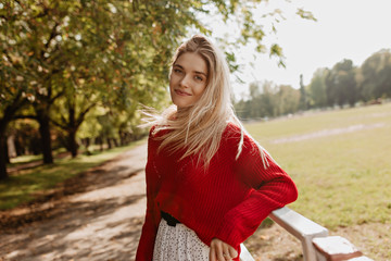 Wall Mural - Cheerful girl with a natural make-up smiling gladly into the camera. Pretty blonde happily posing in the autumn park.