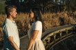 © Pajaros Volando - Man and woman looking each other and smiling while standing on boardwalk. Sunset time, golden hour