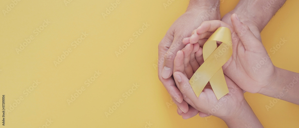 adult and child hands holding yellow gold ribbon, Sarcoma Awareness, Bone cancer, childhood cancer awareness, world suicide prevention day, September Yellow - obrazy, fototapety, plakaty 