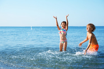 Sticker - Cute little children having fun in sea on sunny day. Beach holiday