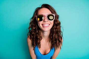 Wall Mural - Closeup photo of shiny lovely girlish lady model beaming smile round pink sun specs curly hairstyle bright playful carefree beach resort wear blue swimsuit isolated turquoise color background