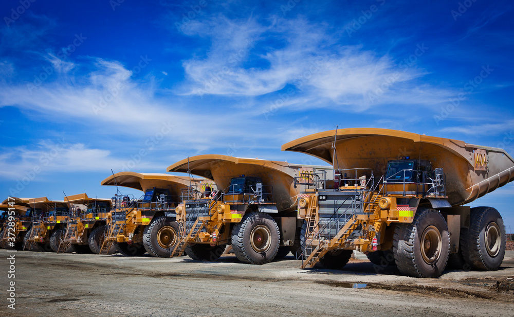 Massive yellow excavation trucks lined up. Used for transporting mine ore. Industrial transportation. All logos removed.