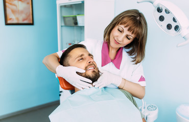 A man treats his teeth at the dentist. Dental examination at the dentist. A snow-white smile. A young smiling man with beautiful teeth undergoing a dental examination. The doctor examines the patient