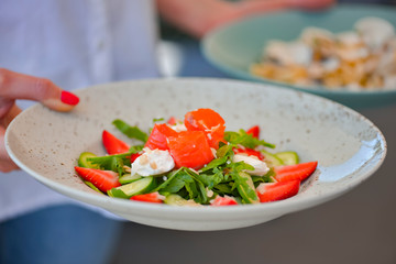 Waiter serving a meal in a restaurant. Salmon salad and pasta. Sea food concept. Eating out in restaurant.