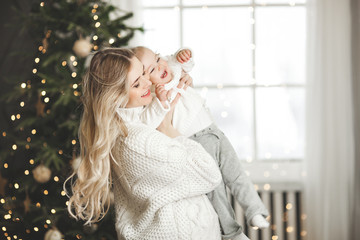 Wall Mural - Attractive young mother with her little baby daughter on christmas background