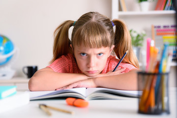 Little girl studying angry with crossed arms at home