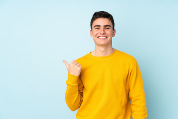 Teenager caucasian handsome man isolated on purple background pointing to the side to present a product