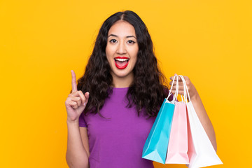 Canvas Print - Spanish Chinese woman with shopping bag over isolated background pointing up a great idea