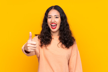 Sticker - Spanish Chinese woman over isolated yellow background with thumbs up because something good has happened