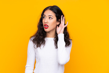 Sticker - Mixed race woman over isolated yellow background listening something