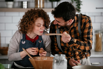 Wall Mural - Boyfriend and girlfriend making delicious food at home. Loving couple cooking in kitchen..