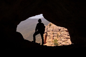 MOUNTAINEER IN A CAVE SITUATED ON THE VERTICAL WALL OF A ROCK MOUNTAIN