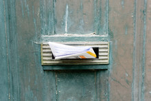 Detail Of The Opening For The Mail Of A Vintage Door With A Sheet Of Advertising Inserted Inside.