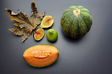 Wall Mural - A slice of ripe and juicy cantaloupe melon and sweet figs on a gray background. Autumn still life with melon and figs. Autumn fruits.