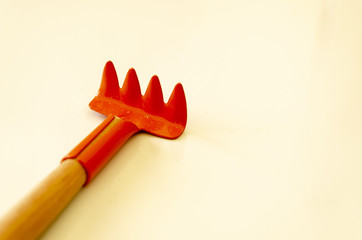 Sticker - Closeup shot of a small red rake with a wooden handle