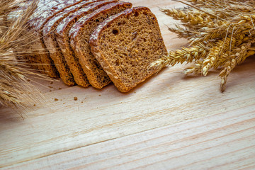 Rustic rye. Fresh loaf of rustic traditional bread with wheat grain ear or spike plant on wooden texture background. Bakery with crusty loaves and crumbs. Design element for bakery product label.