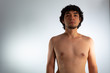 © Antonio Tanaka - Young nude Hispanic man with wavy hair and shaved beard on a white background, expressing confidence