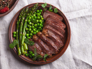 juicy roasted beef sliced steak, with green peas, roasted asparagus, on plate