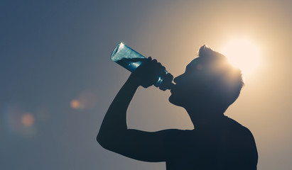 Wall Mural - silhouette of young man drinking a bottle of water