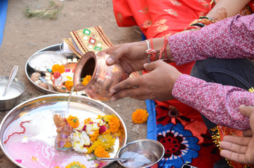 Wall Mural - Closeup of an Indian  man's hands holding a bowl over a plate with flowers