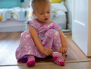 toddler learning how to get dressed, putting on her socks to go out. children development.