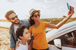 © kleberpicui - Family road trip. Latin family traveling locally by car. Taking self portrait on smartphone