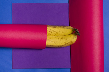 Poster - Overhead shot of bananas wrapped in a pink fabric on a colorful texture