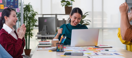 Poster - Asian female leader and ux/ui designer clapping hand for successful of mobile app interface wireframe design on table at modern office.Creative digital development agency