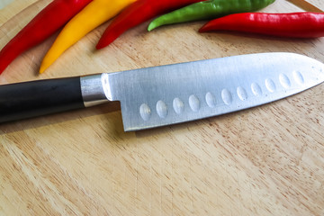 Sticker - Closeup shot of colorful chili peppers next to a knife on a wooden surface