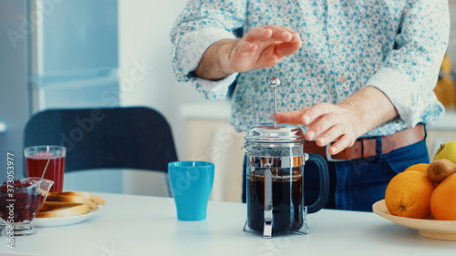 Older man making coffee using french press for breakfast in kitchen. Elderly person in the morning enjoying fresh brown cafe espresso cup caffeine from vintage mug, filter relax refreshment