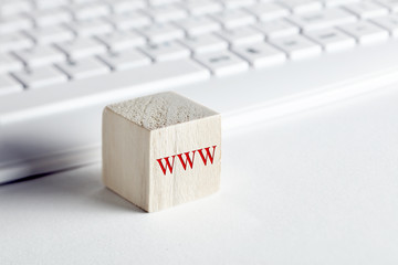 The word www, world wide web written on wooden block with computer keyboard background.