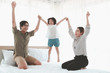 © Stella - Happy family having fun in the bedroom. Father, mother and daughter spending time together, child jumping on the bed, parents and kid having good memory and playing together at home