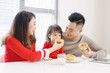 © makistock - Young Asian family having breakfast in kitchen.