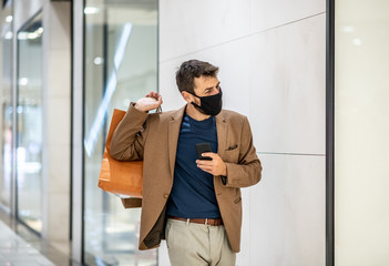 A young man carries shopping bags with a mask on his face, shopping during a pandemic caused by a virus