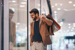 © Sanja - A man walks through a shopping mall with a smile on his face and bags in his hand and looks at the shop windows